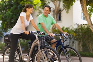 A joyful couple riding bicycles together outside on a sunny day, embracing an active and healthy lifestyle.